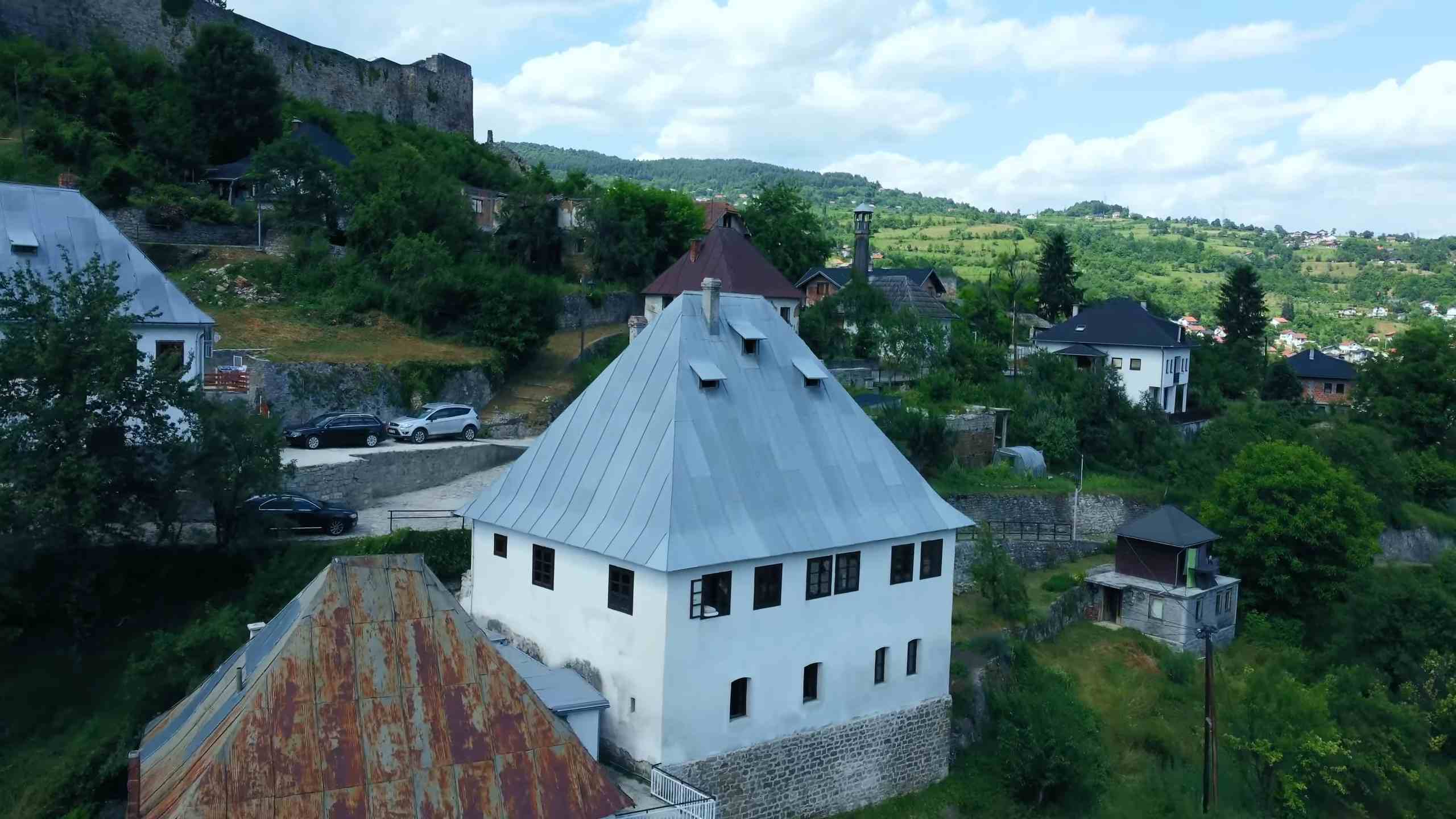 Pogled na tradicionalne kuće i tvrđavu u Jajcu, okružene zelenilom i brdima